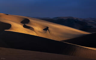 sunset image of sun shining on a slice of desert dunes in Namibia, Africa.