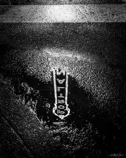 black and white Portland sign lit up as seen reflected form a puddle on the street in portland oregon